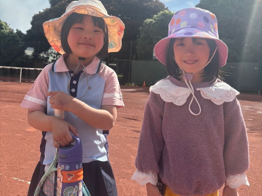 Two young beginner players in sun hats holding racquets courtside at Temp Tennis, Vermont South