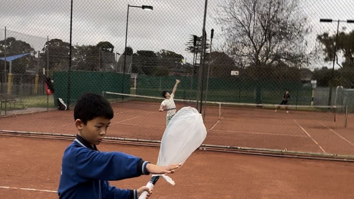 Junior tennis players rallying on the clay courts during a group class